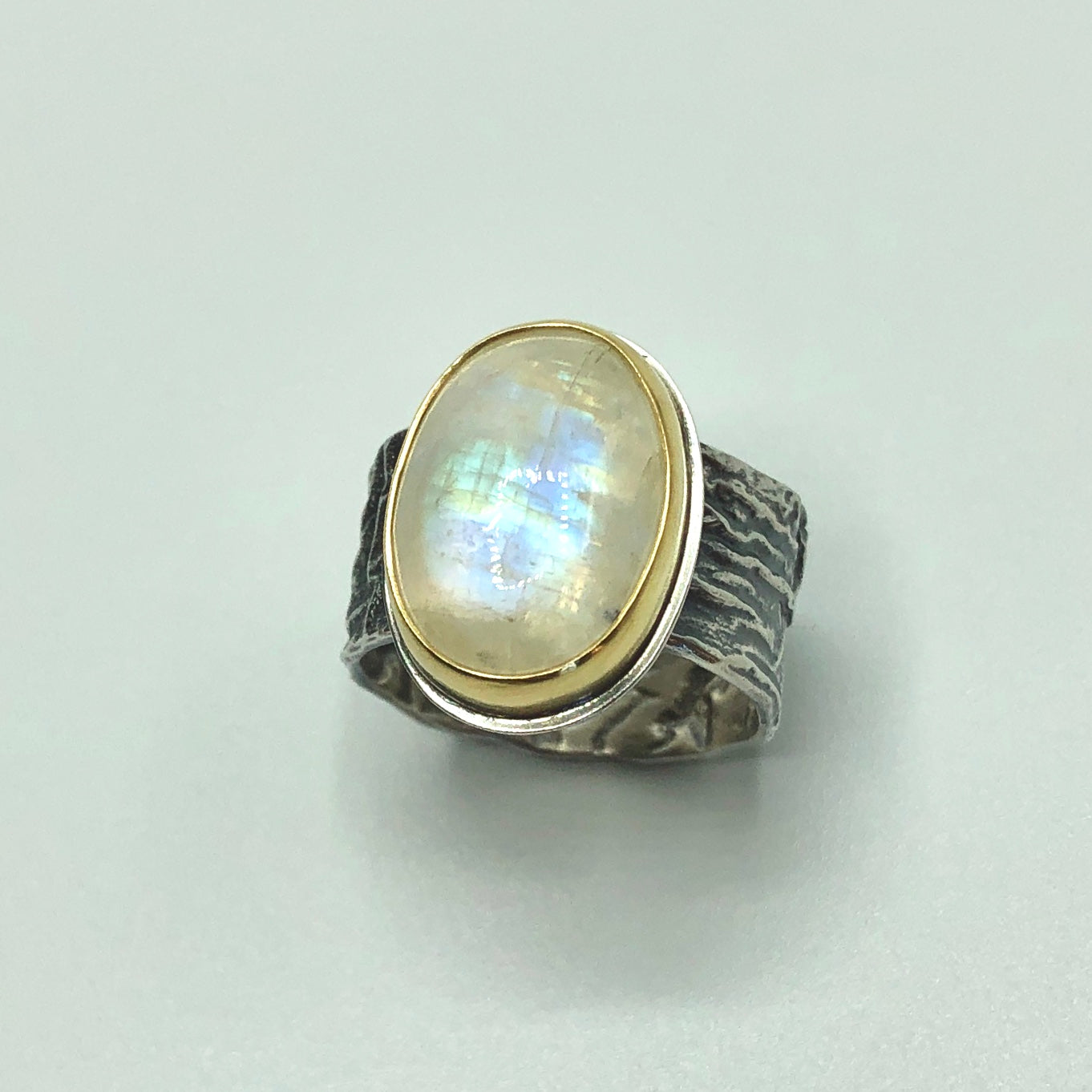 Rainbow Moonstone set in 18k gold bezel and reticulated silver band